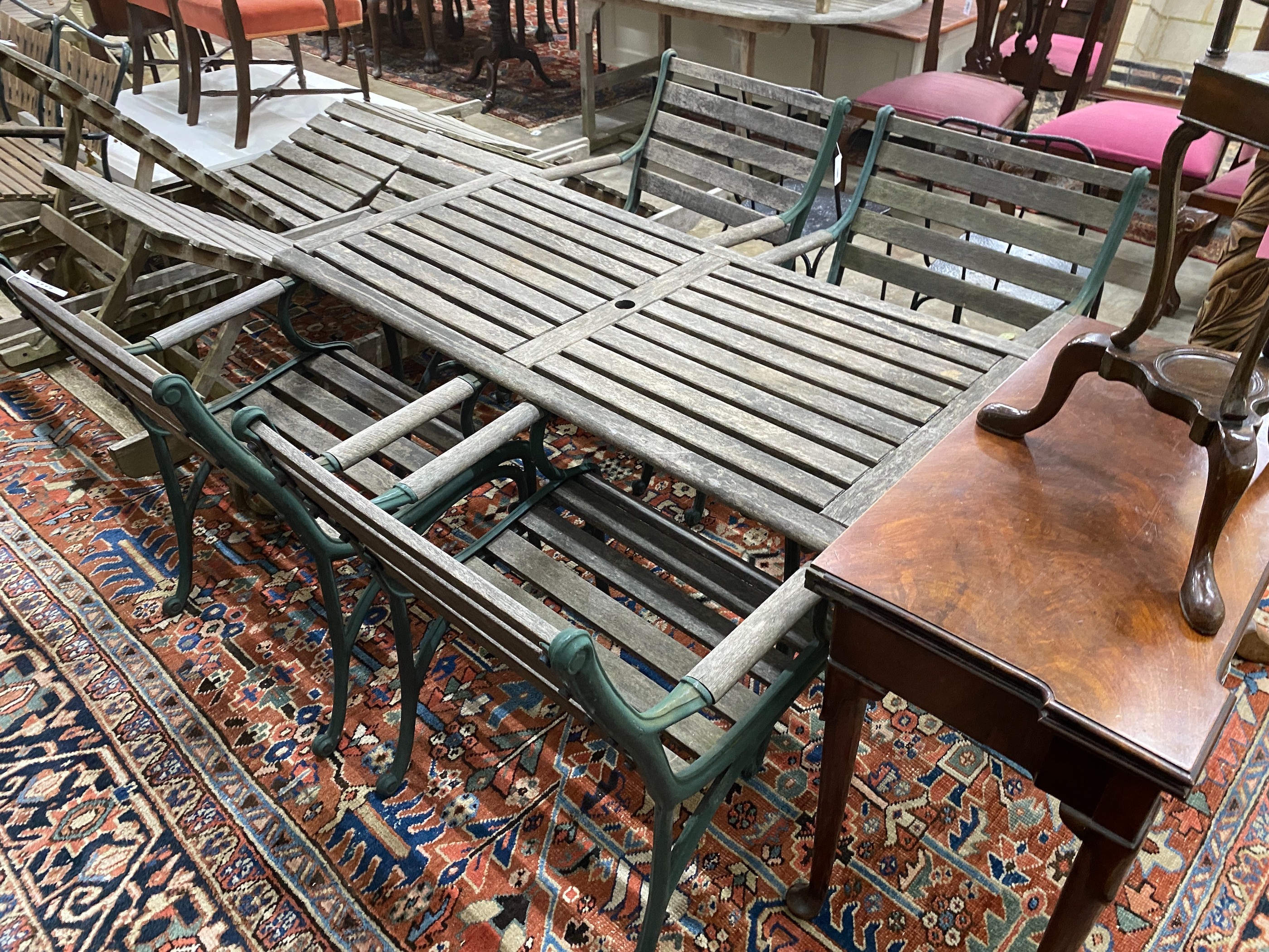 A rectangular slatted wood and cast metal garden table, length 137cm, depth 67cm, height 64cm together with four similar elbow chairs